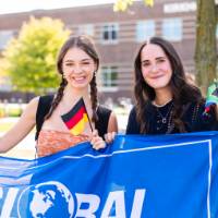 Two students holding "Global GVSU" flag